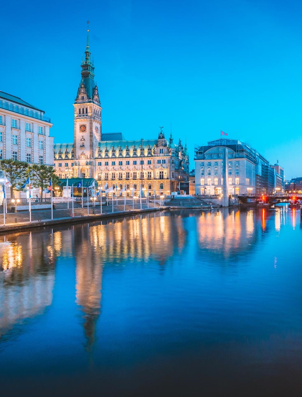 Classic twilight view of Hamburg city center with historic town hall reflecting in Binnenalster during blue hour at dusk, Germany